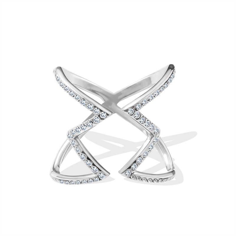 Bague large argentée au design géométrique ajouré en forme de X, pavée de petits cristaux blancs transparents et brillants sur les lignes avant, présentée de face avec ombre portée.
