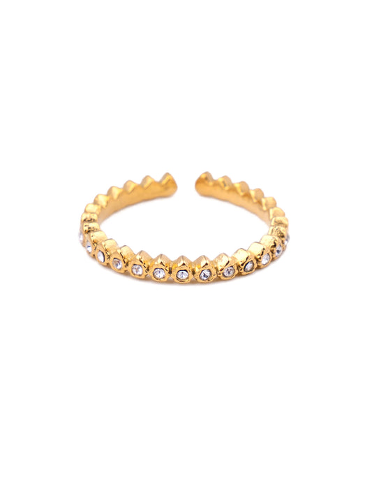 Bague fine ajustable en acier inoxydable doré avec un anneau sculpté en pointes géométriques et pavé sur l'avant d'une rangée de petits oxydes de zirconium ronds blancs, photographiée de face sur fond blanc épuré.