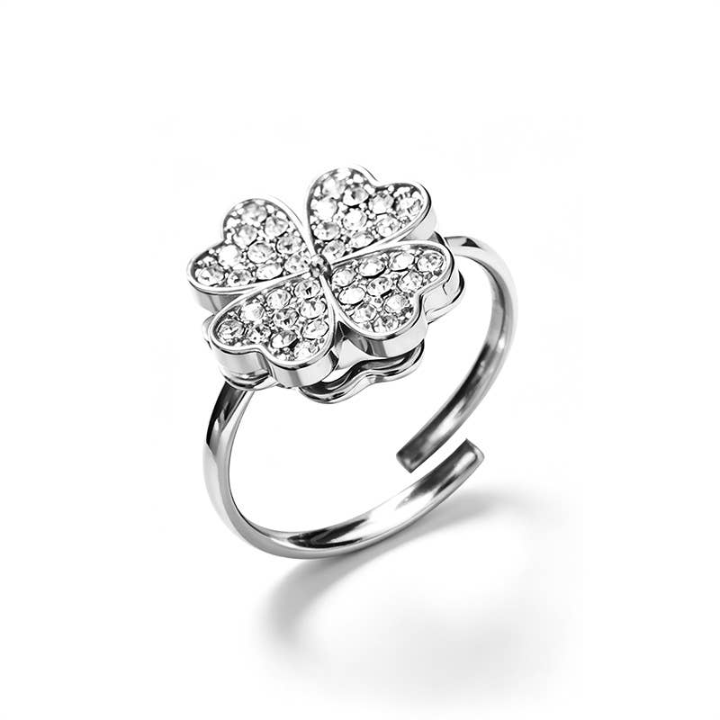 Bague anti-stress ajustable en acier inoxydable argenté, ornée d'un trèfle à quatre feuilles rotatif pavé de cristaux brillants.
