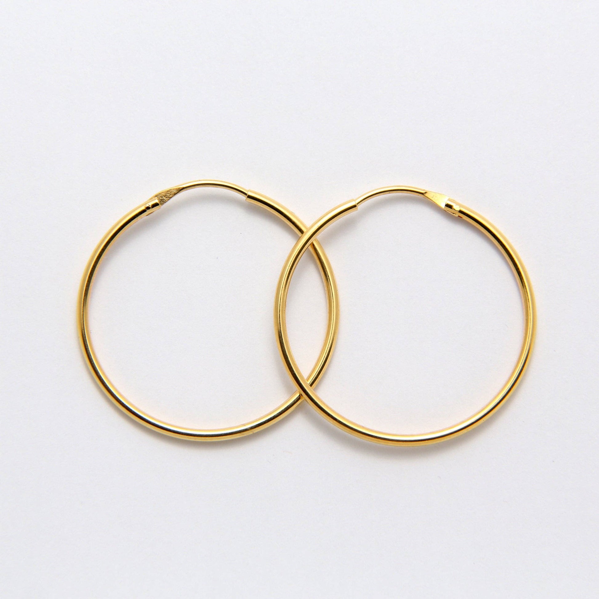 Boucles d'oreilles Alba REF 144 - Paire de créoles dorées moyennes pour femme en fil rond lisse et brillant avec fermoir invisible intégré.