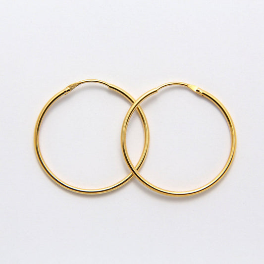 Boucles d'oreilles Alba REF 144 - Paire de créoles dorées moyennes pour femme en fil rond lisse et brillant avec fermoir invisible intégré.