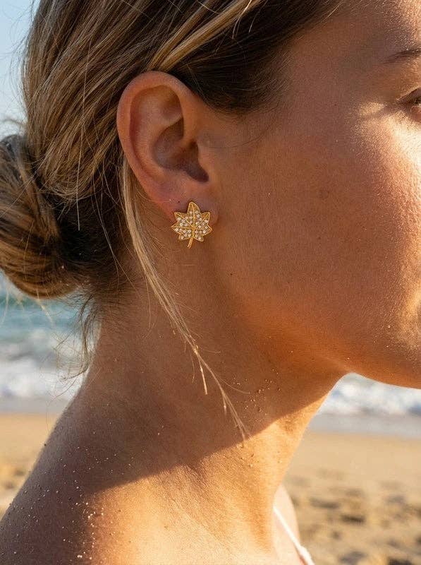 Boucles d'oreilles puces en forme de feuille en acier inoxydable doré, pavées de cristaux scintillants et portées au lobe à la plage.
