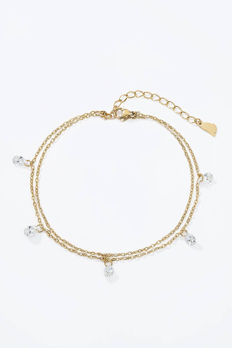 Bracelet de Cheville Double Rang et Gouttes Étincelantes REF 166 - Chaîne de cheville double rang dorée en acier inoxydable pour femme avec 5 cristaux clairs en forme de gouttes suspendues.