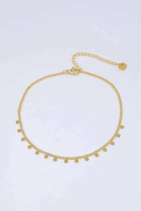 Bracelet de cheville en acier inoxydable doré posé à plat, doté d'une fine chaîne ornée de petites pampilles rondes et lisses avec chaînette d'extension.