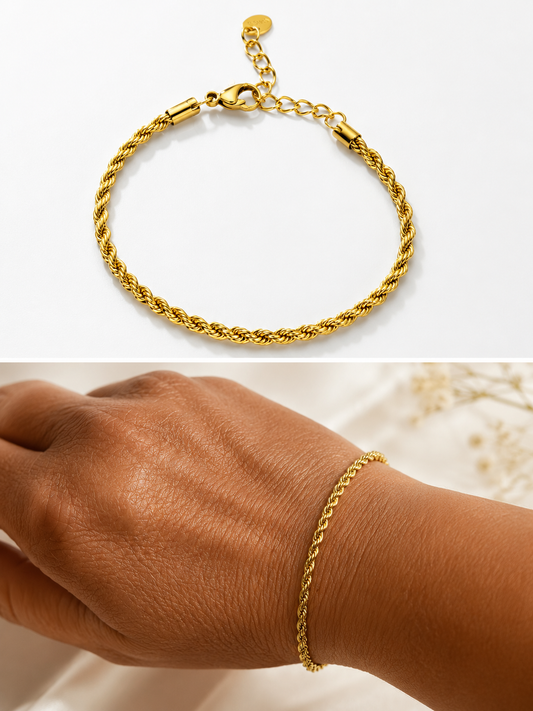 Bracelet fin en acier inoxydable doré à maille tricotée texturée et scintillante en relief, porté au poignet sur fond de tissu satiné plissé beige.