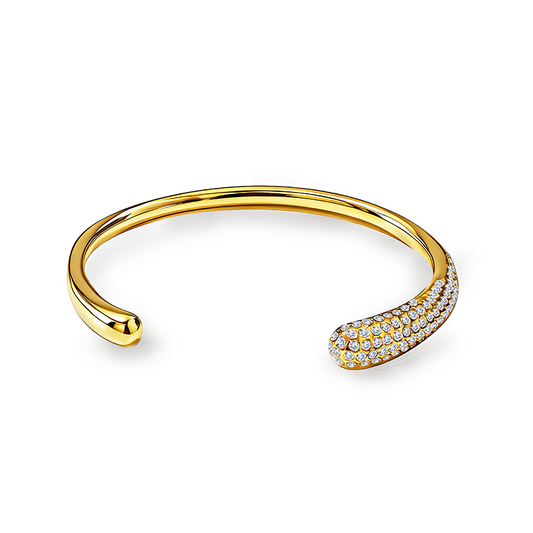 Bracelet jonc ouvert doré pour femme en acier inoxydable poli avec une extrémité en forme de goutte bombée pavée de cristaux brillants.