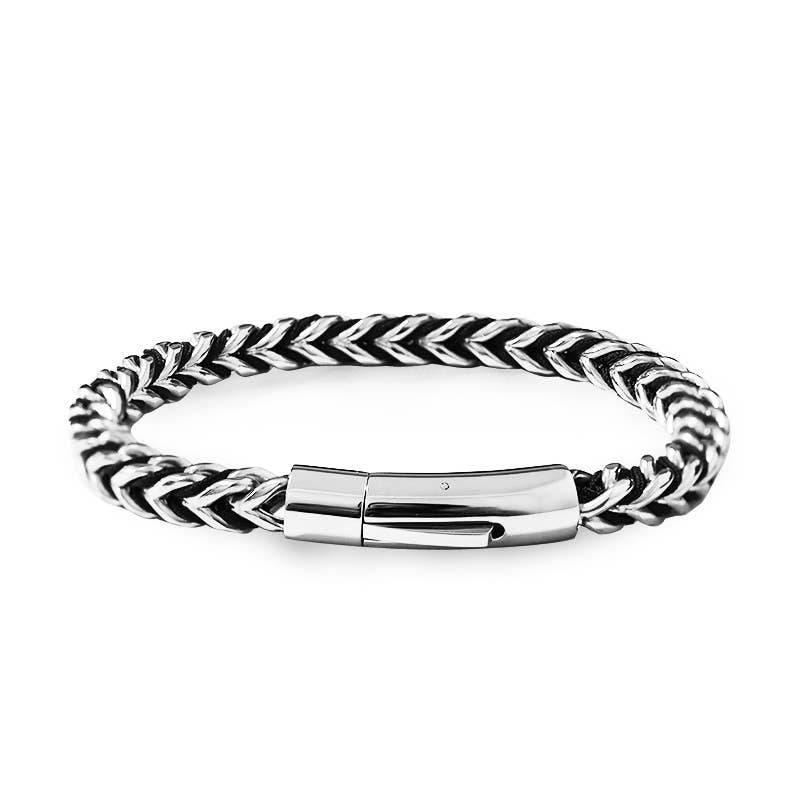 Bracelet pour homme en acier inoxydable argenté doté d'une maille épaisse tressée en épi de blé avec reliefs ombrés noirs, équipé d'un fermoir cylindrique à cliquet poli, sur fond blanc.
