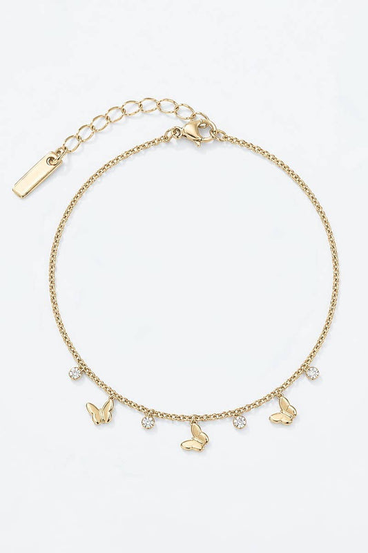 Chaîne de cheville dorée pour femme en acier inoxydable avec breloques papillons bombés et cristaux blancs suspendus.
