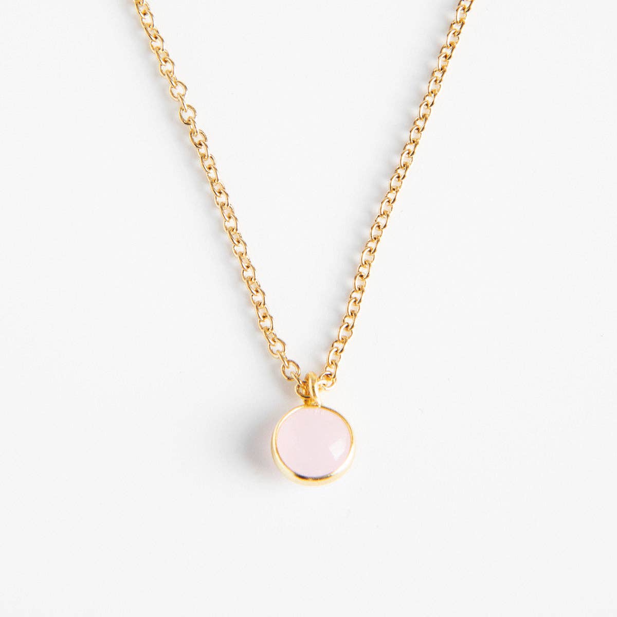 Collier doré Céleste REF 147 pour femme avec chaîne fine en maille forçat et pendentif rond serti clos couleur rose poudré pastel facettée.