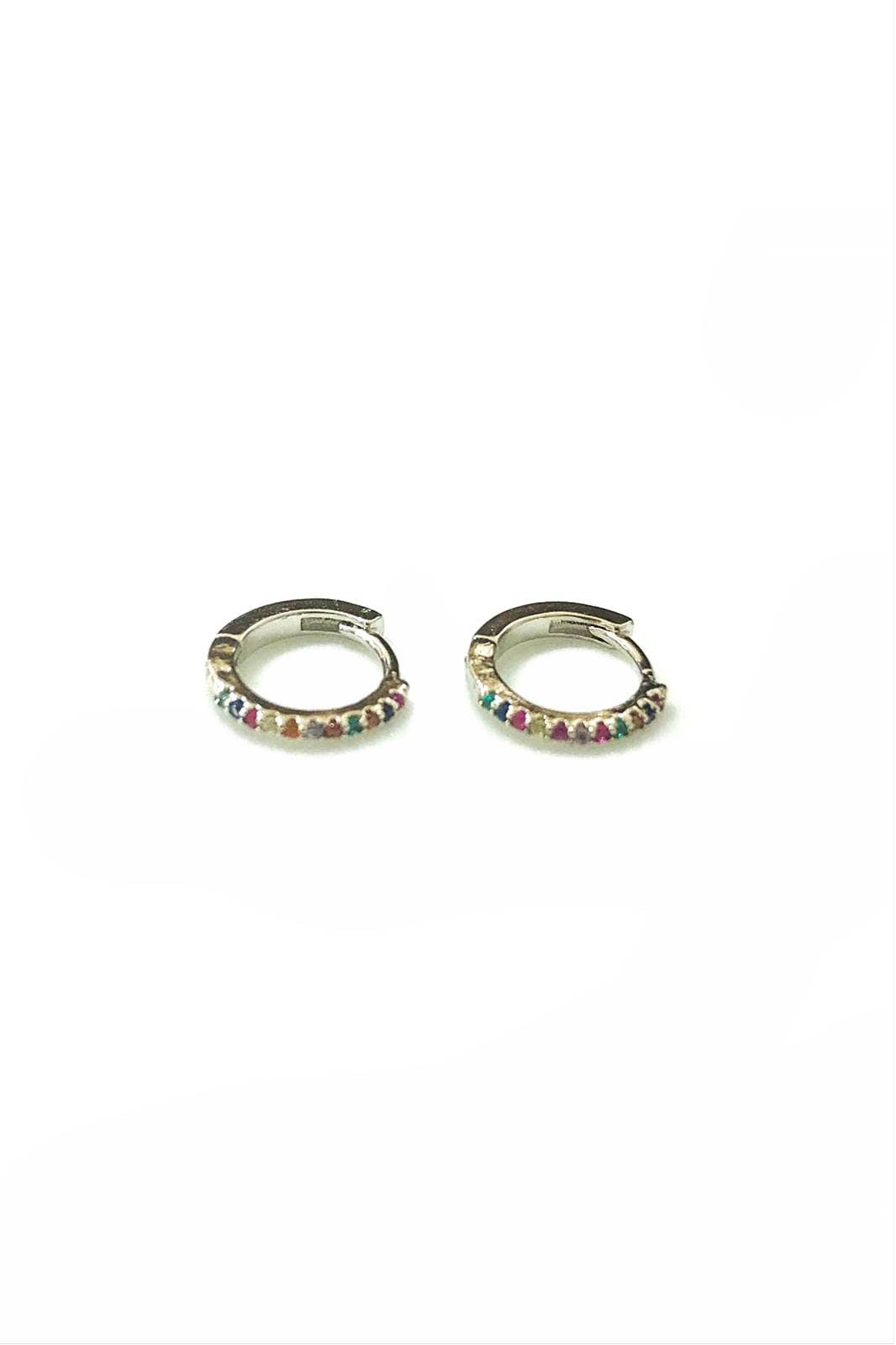 Paire de mini boucles d'oreilles créoles argentées en acier poli brillant, serties de petits strass précieux multicolores disposés le long de l'anneau, photographiées sur fond blanc.