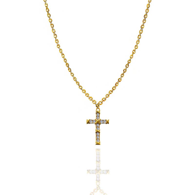 Collier avec chaîne en maille jante dorée et pendentif en forme de croix ouvragée, sertie de cristaux blancs brillants, présenté de face avec son reflet sur fond blanc épuré.