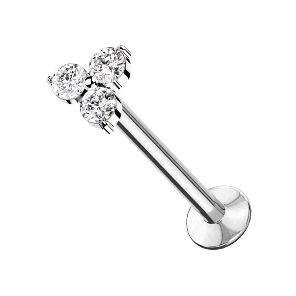 Piercing de type labret argenté à fond plat orné d'un motif trinité composé de trois cristaux blancs ronds et étincelants, présenté de trois-quarts sur fond blanc.