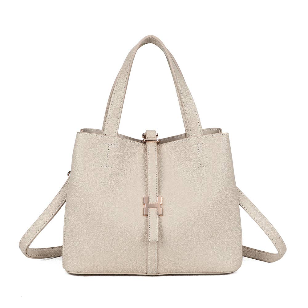 Petit sac cabas évasé Alba couleur beige nude (REF 5) doté de ses anses, de sa bandoulière amovible et d'un ornement central en métal doré, sur fond blanc.