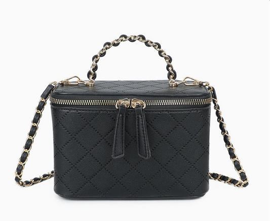 Sac à main rigide de style vanity case en cuir noir matelassé avec double fermeture éclair dorée, une poignée supérieure et une bandoulière en chaîne dorée entrelacée de cuir, isolé sur fond blanc.